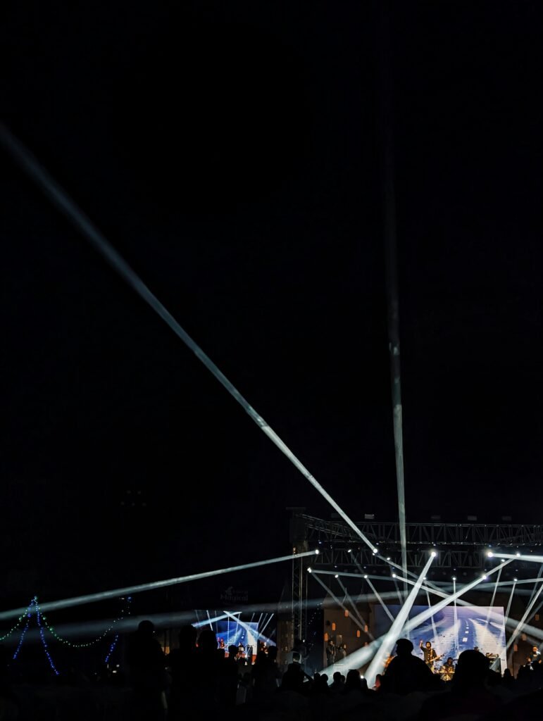 Dramatic concert stage lights and lasers representing the high-tech production of the Bad Bunny Super Bowl Halftime Show.