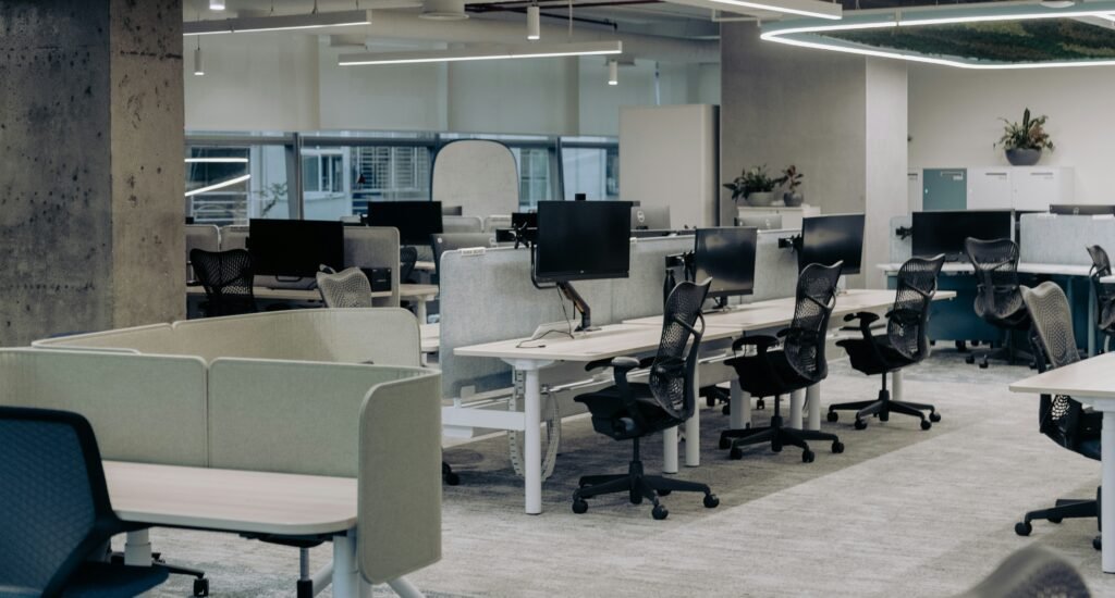 Empty modern open-plan office with rows of unoccupied desks and computers, illustrating the high vacancy rates driving the commercial real estate banking crisis.