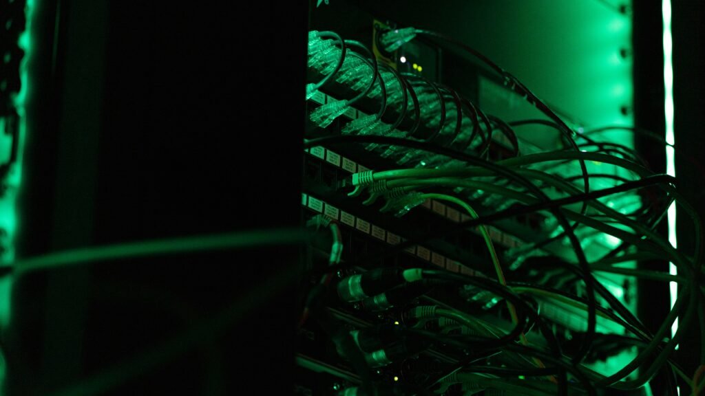 Dark high-tech server room cables with green lights representing the AI infrastructure driving the SaaSpocalypse.