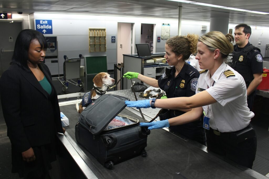 TSA officers inspecting luggage at US airport security checkpoint during operational strain
